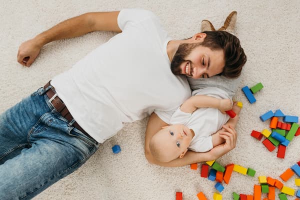 Padre sonriente tumbado al lado de su hijo